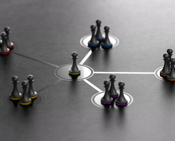 Organized groups managed by a leader. 3D ilustration of pawns with different colors over black background.